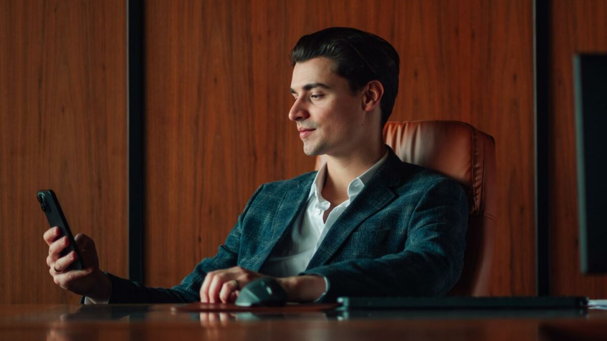 Young businessman checking smartphone in dark wood office